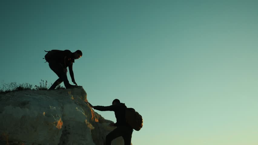 silhouette hiker man tourists hands help climber climbs a mountain. walking tourist hiking adventure climbers sunset climb the mountain . slow motion video. hiker sunlight on top win victory the hill Royalty-Free Stock Footage #1018815049