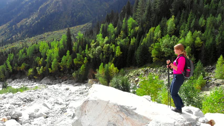 Hiker girl standing on the top of mountain, enjoying beautiful view of mountain river flowing. Hiking and explore nature concept. 