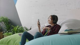 happy woman student using smartphone browsing online social media messages enjoying lunch break relaxing on colorful pillows listening to music in modern office - Powered by Shutterstock - Get 15% off with code: PIKWIZARD15