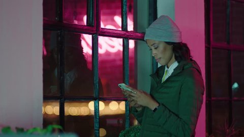 young african american business woman using smartphone texting browsing online social media messages on mobile phone looking out window planning ahead in office at night