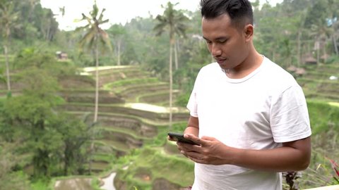 asian young man using smartphone in rice field in Bali