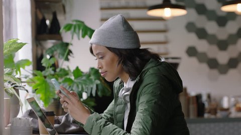 young african american woman using smartphone in cafe browsing online reading social media messages texting enjoying drinking coffee relaxing in trendy restaurant