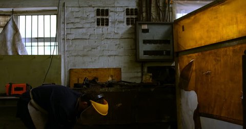 Attentive Caucasian metalsmith using welding torch in workshop 4k