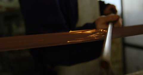 Close-up of caucasian metalsmith sharpening metal rod in workshop 4k