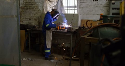 Attentive metalsmith using welding torch in workshop 4k