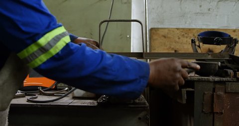Mid section of African-american metalsmith working on machine in workshop 4k