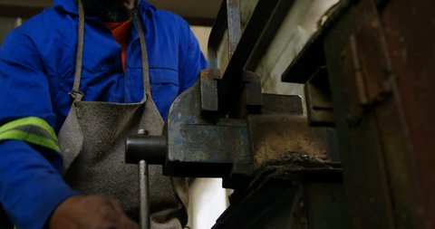 Attentive African-american metalsmith working on machine in workshop 4k