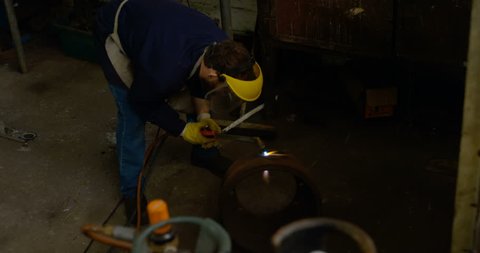 Attentive Caucasian metalsmith using welding torch in workshop 4k