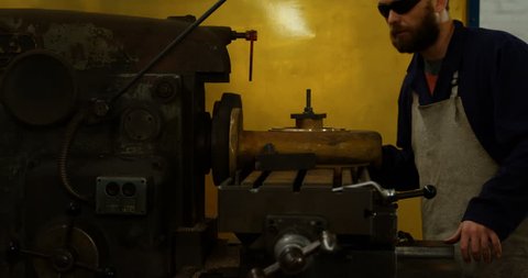 Attentive Caucasian metalsmith operating machine in workshop 4k