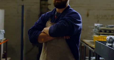 Portrait of caucasian metalsmith standing with arms crossed in workshop 4k