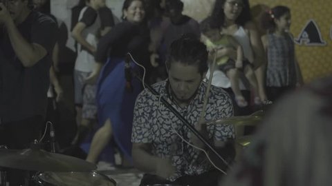 Manaus, Brazil - 2017
Wide shot showing a drummer of a band performing for a crowd, who can be seen dancing in the background.