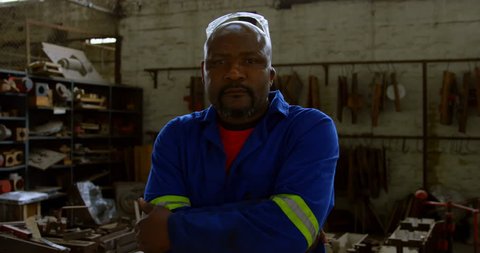 Portrait of African-american metalsmith standing with arms crossed in workshop 4k