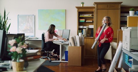 Busy bustling industrial modern architect office full of professional women in the daytime. Wide to medium shot on 4K RED camera on a gimbal tracking backwards.