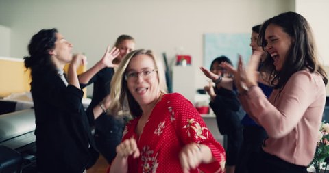 Dance party with female business professionals in industrial modern architect office during the daytime. Medium shot on 4K RED camera on a gimbal.