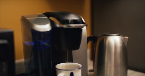Office worker makes single serve coffee pod and drinks it in company kitchen. Closeup shot on 4K RED camera.