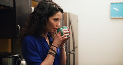 Smiling female office worker pours coffee and drinks it in office kitchen. Medium shot on 4K RED camera on a gimbal.
