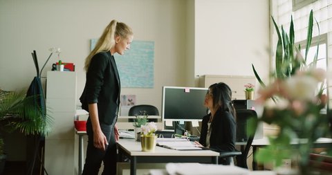 Shy Asian business woman endures yelling by hostile female coworker in office during the daytime. Medium to wide shot on 4K RED camera on a gimbal.