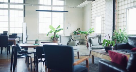 Modern renovated gorgeous hipster wood empty office with couch and plant corner during the daytime. Wide and long shot on 4K RED on a gimbal.