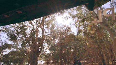 Beautiful woman wearing a hat and sunglasses driving an ATV along the beach through a forest area in Australia, bright natural lighting. Medium shot on 4k RED camera.