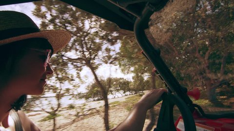Beautiful woman wearing a hat and sunglasses driving an ATV along the beach through a forest area in Australia, bright natural lighting. Medium shot on 4k RED camera.