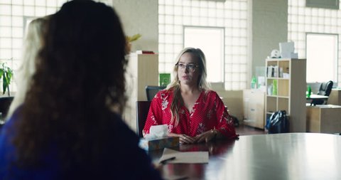 Female worker gets sad news at big board room table in hipster industrial office during the daytime. Wide to medium shot on 4K RED on a gimbal.