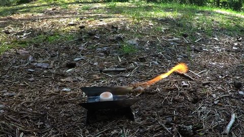 The dry spirits tablet burns on a metal plate in the woods