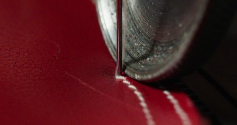 Close up of a shoemaker sewing a red leather by using a sewing machine according to the italian tradition. Concept: handmade, fashion, industrial, factory.