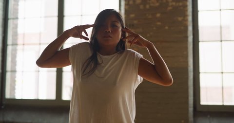 Angelic asian dancer pirouettes in industrial wood and brick windowed loft during daytime. Wide to long shot on 4K RED camera.