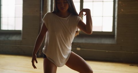 Contemporary dancer dances in industrial wood and brick windowed loft during daytime. Wide to long shot on 4K RED camera.