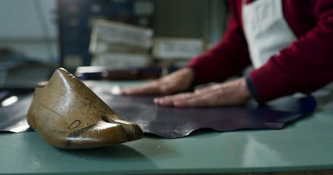 Close up of a shoemaker working a fabric in a shoe factory he is using the italian tradition. Concept: handmade, fashion, industrial, factory.
