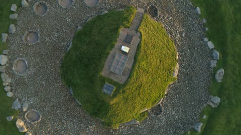 Cairnpapple Hill, near Torphicen in West Lothian, Scotland. A Neolithic ceremonial henge monument. Aerial footage flying up from the mound, brightly lit by a low sun on one side.