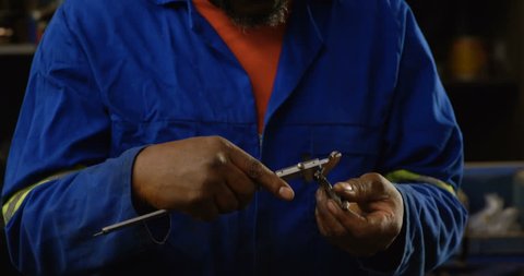 Close up of attentive African-american metalsmith using caliper in workshop