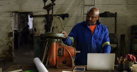 Attentive African-american metalsmith using laptop in workshop 4k