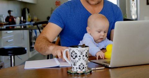 Close up of Caucasian father using laptop while baby boy playing with toy at home, Working from home in quarantine lockdown. Social distancing Self Isolation