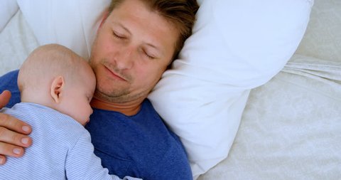Close up of Caucasian father and baby boy sleeping in bedroom at home Social distancing and self isolation in quarantine lockdown for Coronavirus Covid19