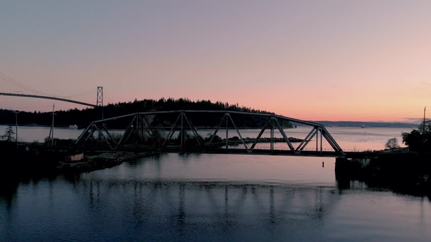 Aerial shot of downtown Vancouver, Stanley Park, and the Lions Gate Bridge at sunset.