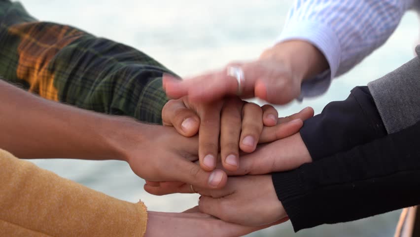 Arm stacked together one by one in unity and teamwork. Many hands getting together in the center of a circle. Close up outdoor shot. Many hands connecting in nature. | Shutterstock HD Video #1018844893