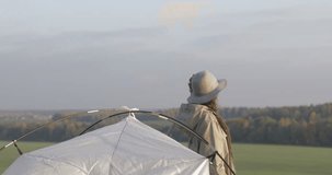 The girl sets up a tent on the grass. Tourist fortifies the tent, camping. Female caucasian model on vacation 4k video