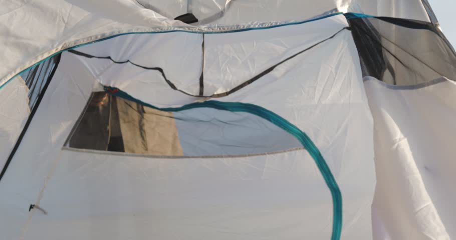 The girl sets up a tent on the grass. Tourist fortifies the tent, camping. Female caucasian model on vacation 4k video