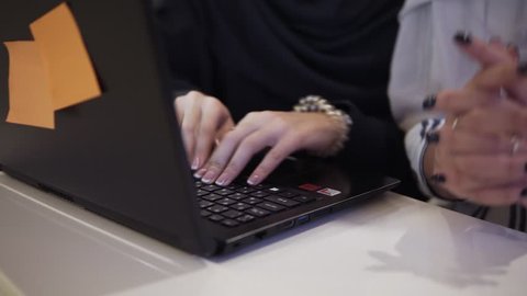 Accelerating footage of happy muslim businesswomen in hijab at office workplace or conference hall. Two smiling arabic woman working on laptop on startup project together, copy space