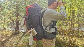 Traveler photographing scenic views in forest by mountain river. Man shooting picturesque views. The guy takes photo and video on old retro camera on film. Professional photographer traveler.