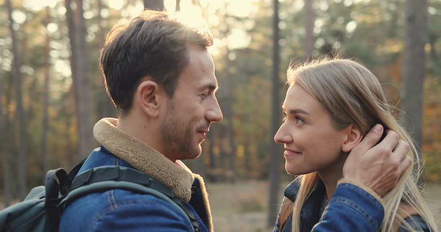 Close up of the happy young couple in love looking at each other, embracing and caressing in the autumn wood. Outside. Portrait.