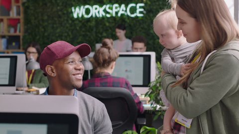 happy business woman mother holding baby playing with colleague discussing project in diverse modern office workplace