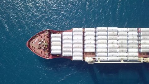 Large general cargo ship loaded with Ammonia containers - Top down aerial footage.