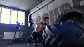 Shirtless man flipping heavy tire at gym for functional training . Muscular fitness . Workout cross training - Powered by Shutterstock - Get 15% off with code: PIKWIZARD15