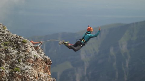 Man jumping off a cliff, rope jumping in the mountains.