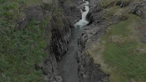 Flying low into Snóksdalur glacial river canyon Iceland, morning light drone aerial.