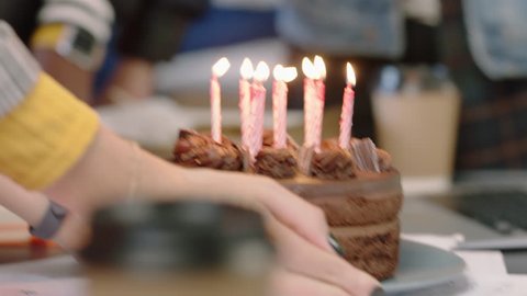 close up business people celebrating birthday party blowing candles on chocolate cake enjoying happy office celebration in cheerful workplace