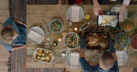 family preparing delicious thanksgiving lunch grandmother taking photo of turkey using tablet sharing celebration enjoying homemade meal together top view tracking