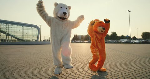 Two funny and cute big growth dolls of bears running, dancing and having fun outdoor.